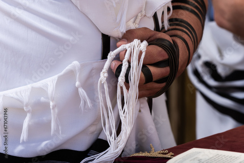 Holding tzitzit around the hand during Jewish prayer photo