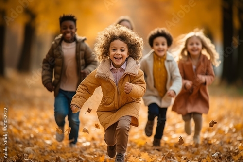 Happy multiethnic children group running along autumn park. Smiling boys and girls of different skin colors play and have fun together. Diversity and free communication concept.