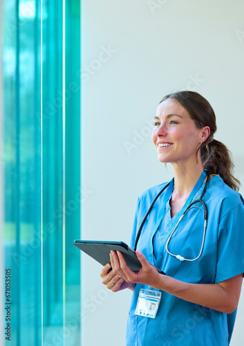 Portrait Of Smiling Female Doctor Wearing Scrubs With Digital Tablet In Hospital