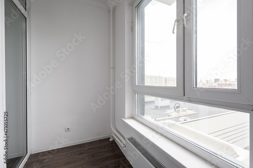 A dirty white glass balcony with windows on the roof of a neighboring house. City view