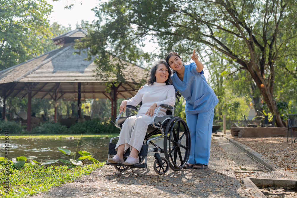 Happy nurse and elderly woman sitting in wheelchair enjoying outdoor. Beautiful nurse with senior woman in wheelchair at outdoor park. Smiling disabled old lady in wheelchair at park. Happy nurse and elderly woman sitting in wheelchair enjoying outdoor. Beautiful nurse with senior woman in wheelchair at outdoor park. Smiling disabled old lady in wheelchair at park.