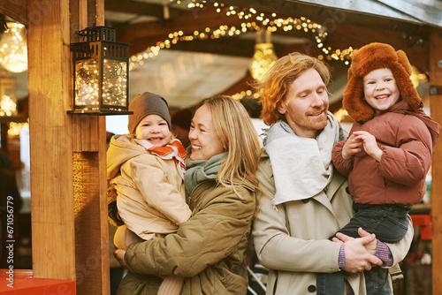 Outdoor portrait of happy young family at Christmas market, parents with 2 little children enjoying holidays, travel with kids © annanahabed