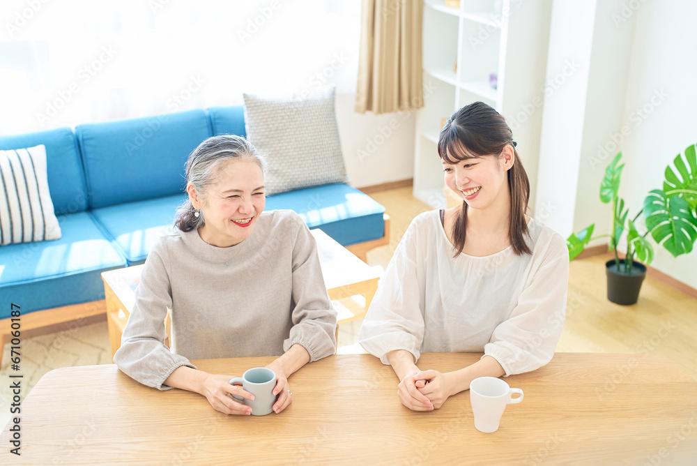 部屋で仲良く話すシニア女性と若い女性 部屋で仲良く話すシニア女性と若い女性