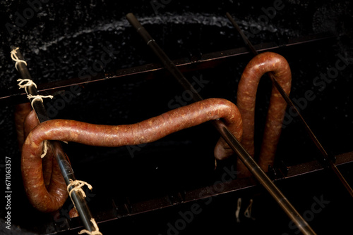 Linguiça de carne de porco sendo defumada em tubo defumador. photo