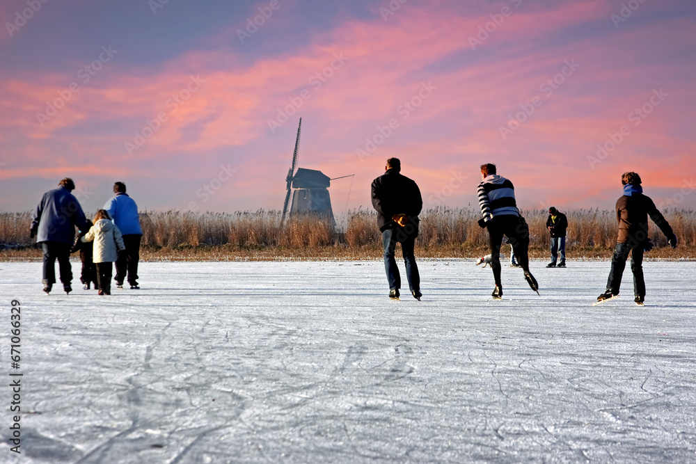 Ice skating at the windmill in the countryside from the Netherlands at sunset - obrazy, fototapety, plakaty 