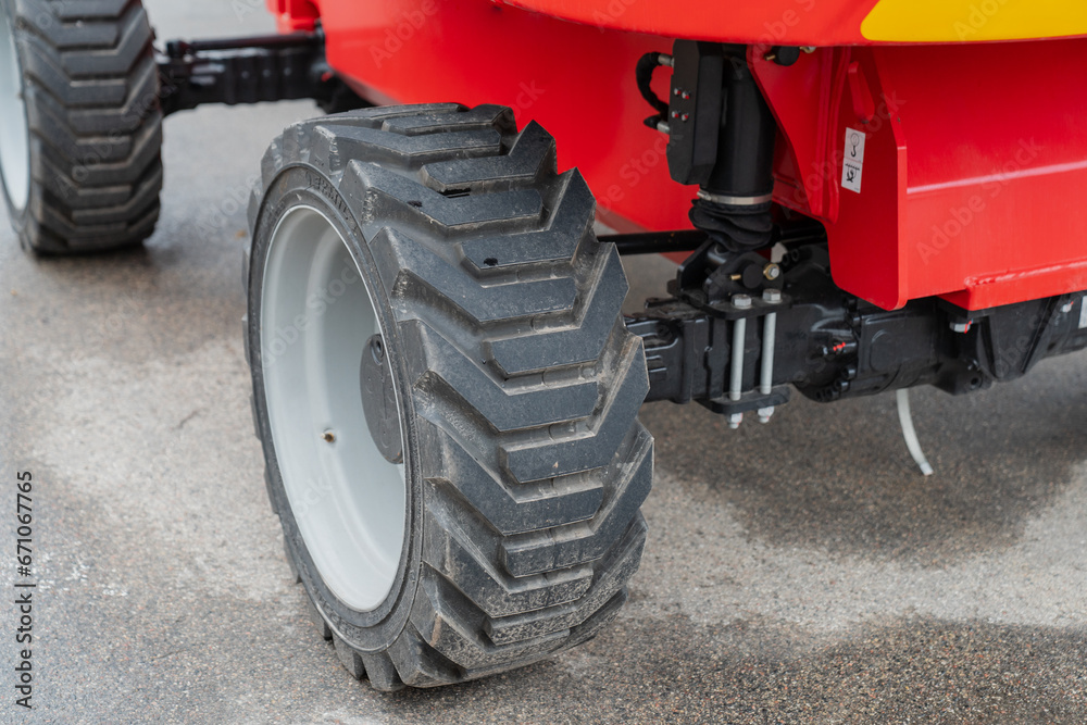 Heavy duty construction lift equipment hard big rubber tyre close up for manufacturing and industrial work on a red lift Heavy duty construction lift equipment hard big rubber tyre close up for manufacturing and industrial work on a red lift