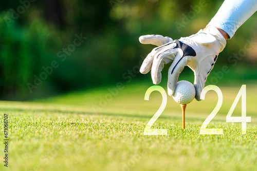 Close up hand Golfer woman putting golf ball for Happy New Year 2024 on the green golf for new healthy.  copy space. Healthy and Holiday Concept photo