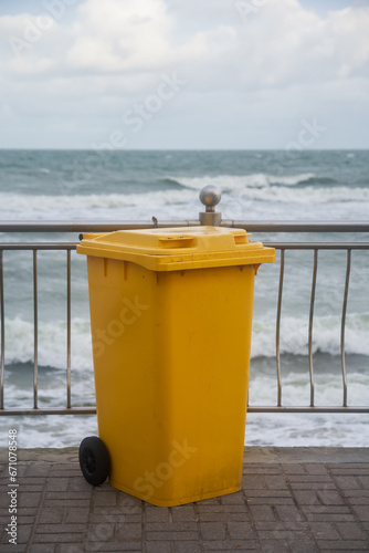 Yellow garbage container by the sea .