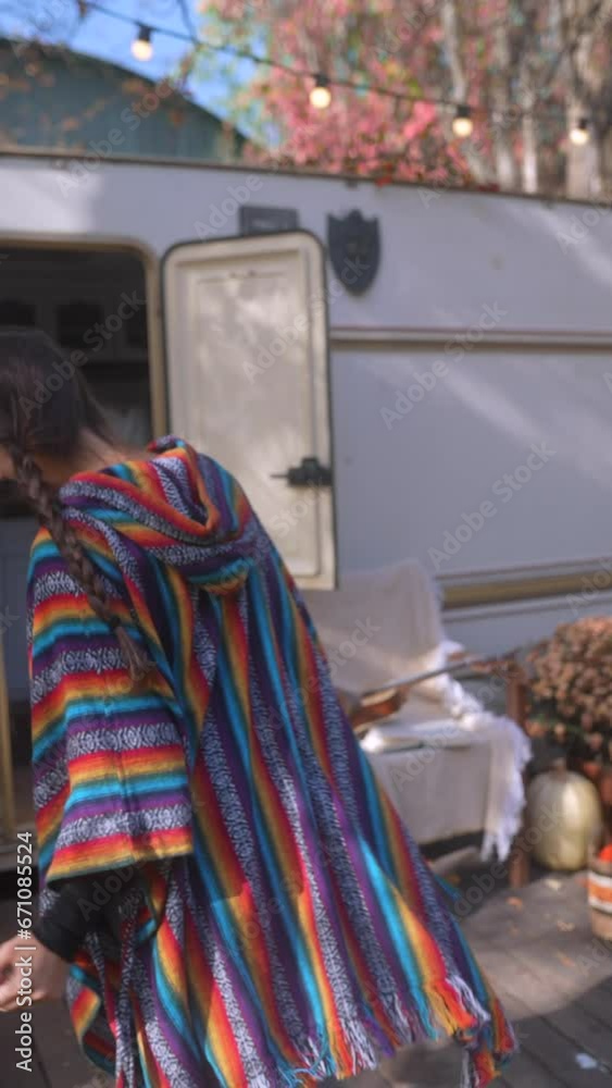 A fashionable and youthful woman, fully immersed in the hippie lifestyle, shares stories about trailer life with a cup of hot drink in hand. A fashionable and youthful woman, fully immersed in the hippie lifestyle, shares stories about trailer life with a cup of hot drink in hand.