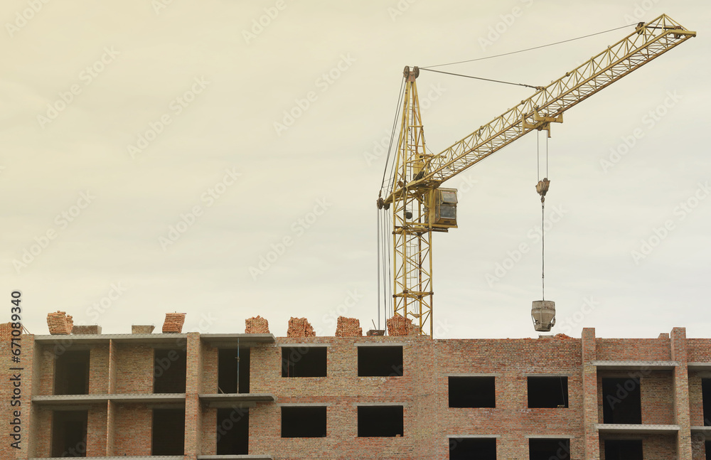 View of a large construction site with buildings under construction and multi-storey residential homes. Tower cranes in action on blue sky background. Housing renovation concept. Crane during