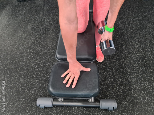 Athlete woman with fitness bracelet on hand lifts dumbbells