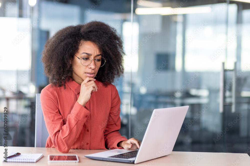 Young successful serious woman at workplace inside office, businesswoman in red shirt working with laptop, thinking about financial solution of project task. Young successful serious woman at workplace inside office, businesswoman in red shirt working with laptop, thinking about financial solution of project task.