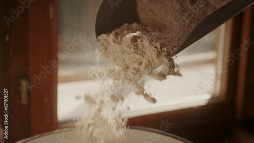 Close-up of fresh white flour in a measuring scoop.  Slow-motion falling flour. Baking ingredients. Traditional concept of flour production.  photo