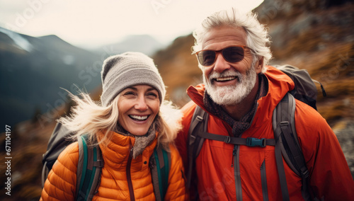 Elderly happy couple with backpacks hiking in the mountains