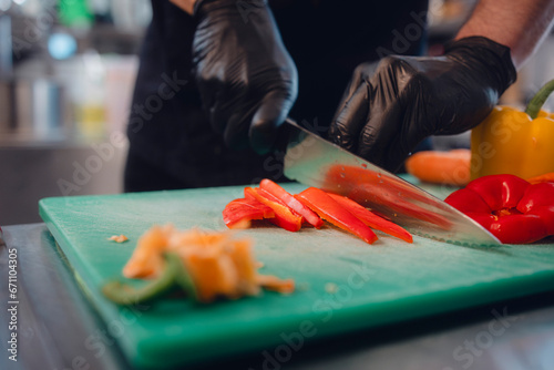 Koch schneidet Gemüse in Küche photo