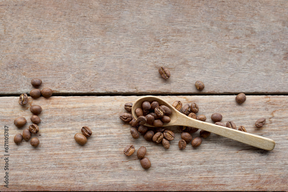 Roasted coffee beans in wooden spoon and spread on wooden table background. It is a medium roast with medium intensity coffee flavor. Slightly sweet and sour, suitable for both hot and cold coffee. Roasted coffee beans in wooden spoon and spread on wooden table background. It is a medium roast with medium intensity coffee flavor. Slightly sweet and sour, suitable for both hot and cold coffee.