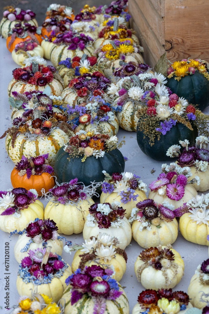 Fall pumpkins decorated with flowers at a vendor at a local farmers market
