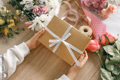 Gift box in hands with flowers at home