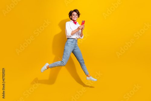 Full length photo of positive lovely girl wear stylish clothes hurrying store buy modern gadget isolated on yellow color background