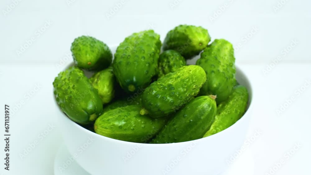 A white plate with fresh green cucumbers is spinning on the turntable. Close-up. View from above A white plate with fresh green cucumbers is spinning on the turntable. Close-up. View from above
