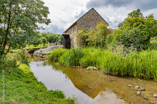 Fototapeta River Geul among wild grass with old Eper or Wingbergermolen watermill in backgr