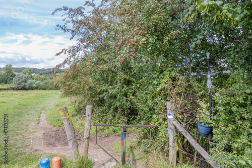 Epen Bronnenland nature reserve, poles with different hiking routes, blue, orange and purple, metal cross with Jesus, countryside in background, sunny day in Gulpen-Wittem, South Limburg, Netherlands photo