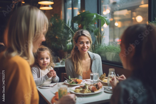 A happy smiling young woman with her little daughter and family in a restaurant and eating brunch.