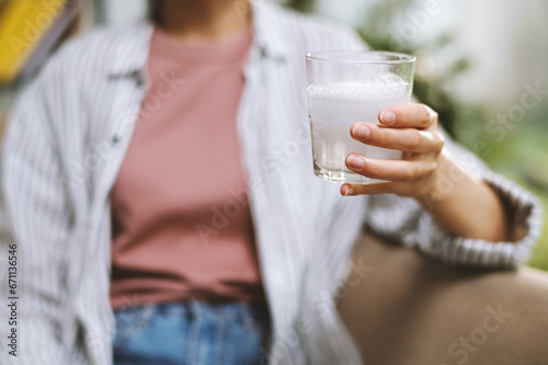 Woman drinking glass of water with dissolving fizzy tablet in the morning