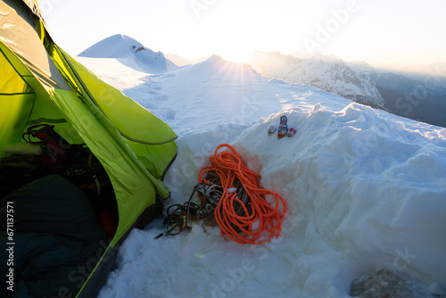 Winterbiwak im Schnee auf einem Berg in den Alpen mit grünem Zelt zum Sonnenaufgang