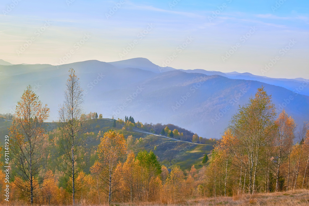 Golden bright autumn dirty road in the mountains in blue haze