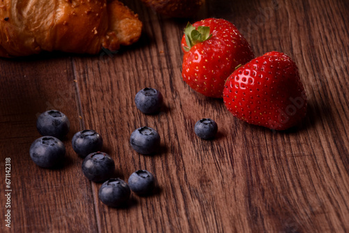 Croissant with strawberries and blueberries on the wood table in the kitchen