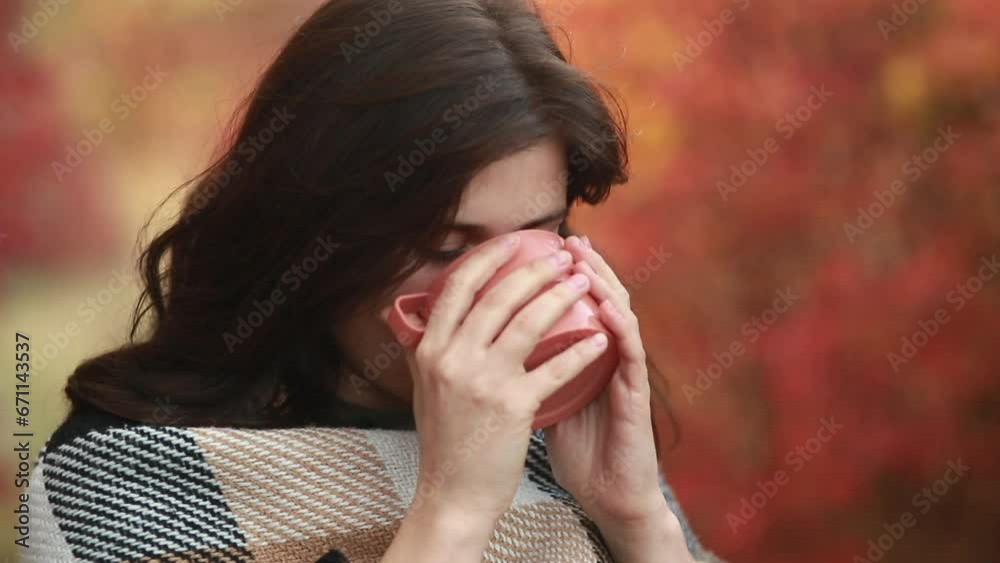 beautiful girl wrapped in warm blanket rests in autumn nature, woman holding cup of hot tea in hands, drinking it and enjoying life beautiful girl wrapped in warm blanket rests in autumn nature, woman holding cup of hot tea in hands, drinking it and enjoying life
