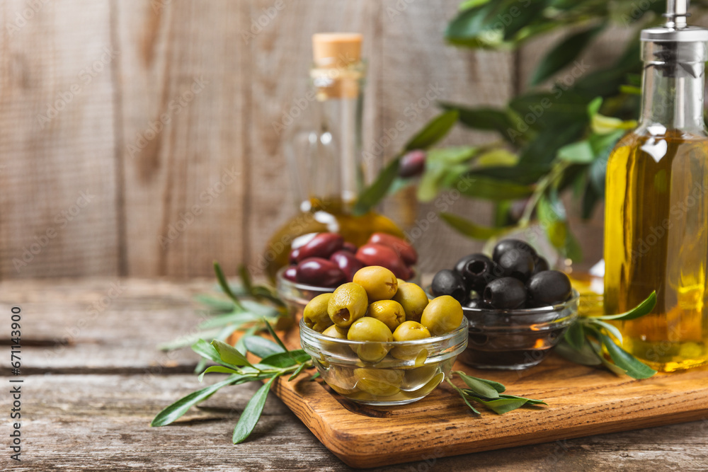 A set of green, red and black olives on background. Various types of olives in bowls and fresh olive leaves. Vegan. Olive fruits. Place for text. Copy space. A set of green, red and black olives on background. Various types of olives in bowls and fresh olive leaves. Vegan. Olive fruits. Place for text. Copy space.