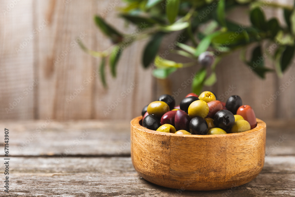 A set of green, red and black olives on background. Various types of olives in bowls and fresh olive leaves. Vegan. Olive fruits. Place for text. Copy space. A set of green, red and black olives on background. Various types of olives in bowls and fresh olive leaves. Vegan. Olive fruits. Place for text. Copy space.