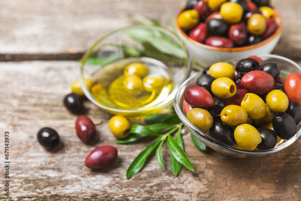 A set of green, red and black olives on background. Various types of olives in bowls and fresh olive leaves. Vegan. Olive fruits. Place for text. Copy space. A set of green, red and black olives on background. Various types of olives in bowls and fresh olive leaves. Vegan. Olive fruits. Place for text. Copy space.