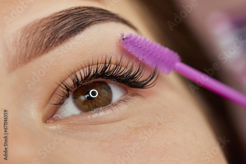 Fotografia master combs the eyelashes of the client after the eyelash extension procedure