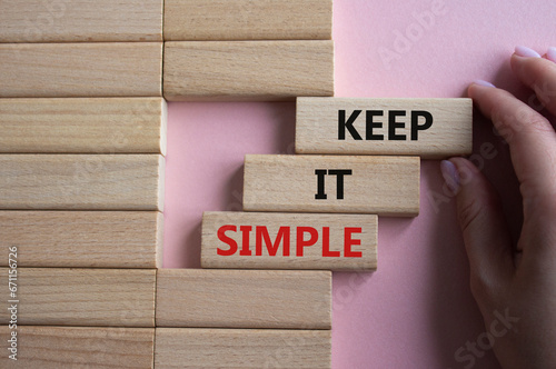 Keep it Simple symbol. Concept words Keep it Simple on wooden blocks. Businessman hand. Beautiful pink background. Business and Keep it Simple concept. Copy space.