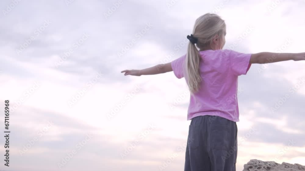 Happy free girl raising her hands up against the background of the sunset sky by the sea Happy free girl raising her hands up against the background of the sunset sky by the sea