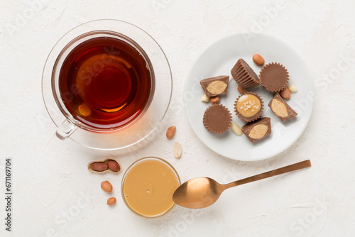 Delicious peanut butter cups with tea on concrete background, top view