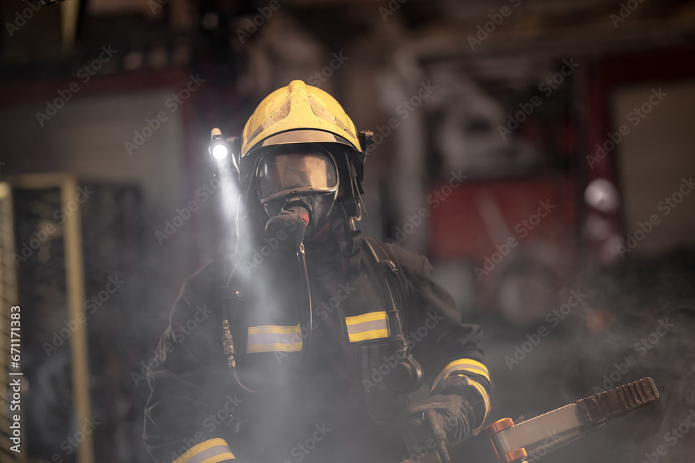 Fireman portrait wearing full equipment and oxygen mask. Firefighter with power hydraulic cutting tool. Smoke and fire trucks in the background. Fireman portrait wearing full equipment and oxygen mask. Firefighter with power hydraulic cutting tool. Smoke and fire trucks in the background.
