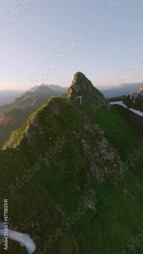 Vertical video. Aerial view sunny mountain range valley running alpine goat wild animal in morning sun. FPV sport drone shot picturesque geology formation landscape industrial tube gazex majestic 4k photo