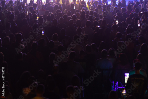 A crowd of spectators watching a performance in dim light.