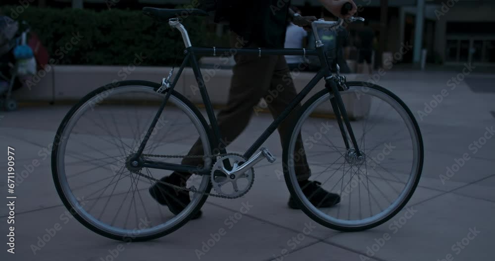 Young professional commutes to the office, walking his bike through the city streets towards metro or train station. Millennial cyclist in urban area. Eco-conscious lifestyle. Young professional commutes to the office, walking his bike through the city streets towards metro or train station. Millennial cyclist in urban area. Eco-conscious lifestyle.