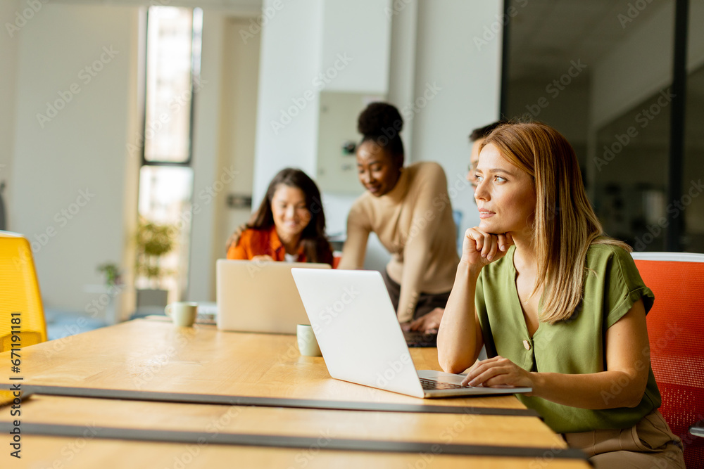 Business woman working on laptop with her young multiethnic startup team working in the modern office Business woman working on laptop with her young multiethnic startup team working in the modern office