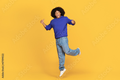 Joyful Young Black Man Jumping In Air And Showing Thumbs Up