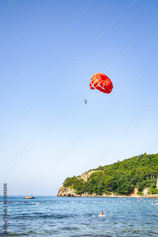 red parachute and blue sky, parasailing in Budva, Montenegro, Europe red parachute and blue sky, parasailing in Budva, Montenegro, Europe