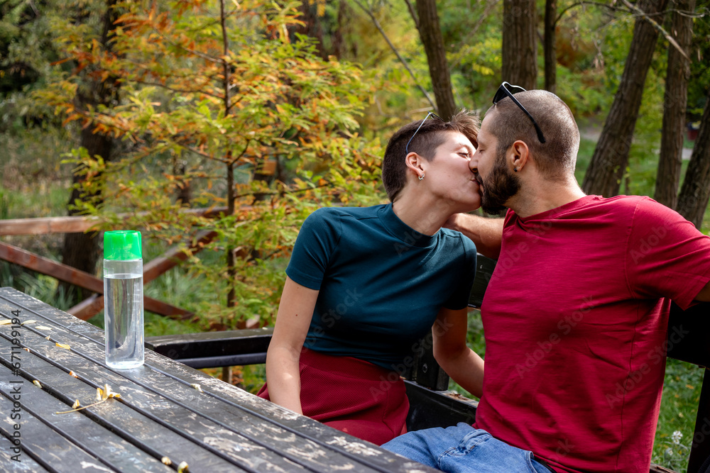 A couple in love sitting and kissing on a bench in the park. A couple in love sitting and kissing on a bench in the park.