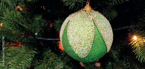 Green ball on a Christmas tree with empty space for text. Christmas decorations, garland and toys. Christmas banner, vector postcard. New Year card, poster with New Year toy.