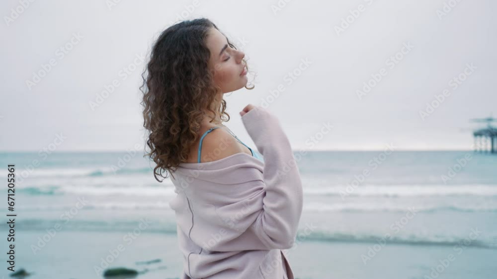 Fashion model RED camera. Gorgeous girl poses at ocean, emotionally looking at camera. Portrait of beautiful curly woman with natural makeup in shiny metallic sheer blouse at beach on gloomy grey day Fashion model RED camera. Gorgeous girl poses at ocean, emotionally looking at camera. Portrait of beautiful curly woman with natural makeup in shiny metallic sheer blouse at beach on gloomy grey day