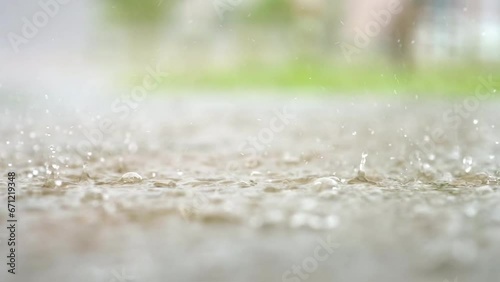 Atmospheric video of rainstorm in a city. Heavy rain and splashes puddles taken from low point. Large drops break on the pavement. Slow motion